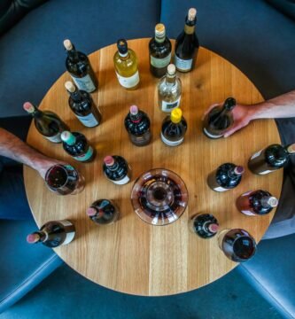 person holding glass bottle on round brown wooden table
